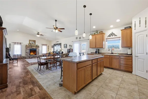 a kitchen with stainless steel appliances kitchen island granite countertop a sink a stove a dining table and chairs