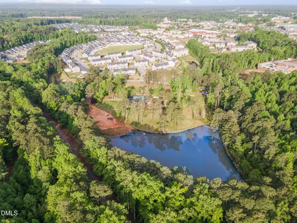 an aerial view of a residential houses with outdoor space and trees all around