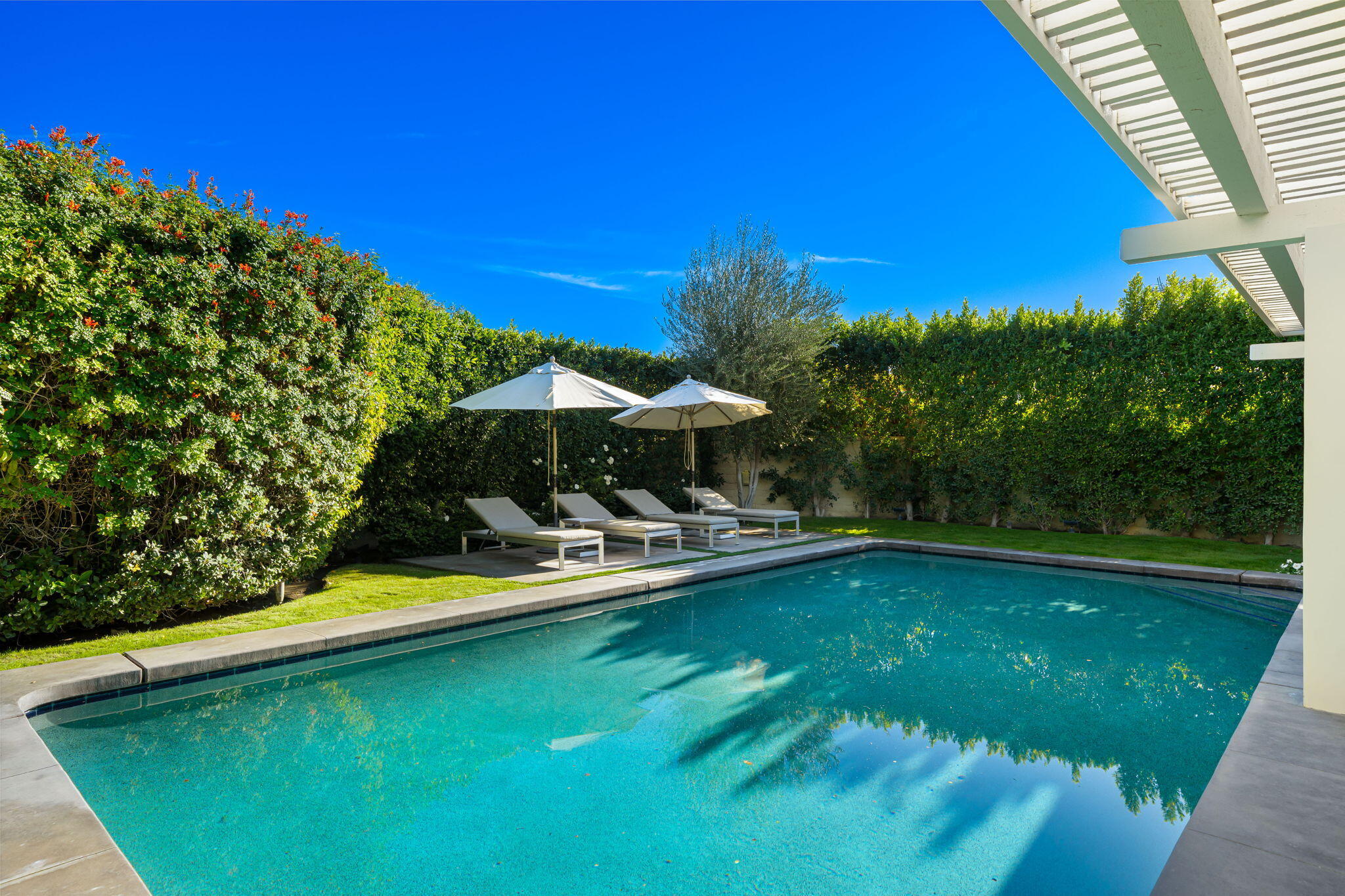 6 Exeter Court Rancho Mirage, CA 92270 - Photo 33 of 54 a view of a swimming pool with lawn chairs under an umbrella