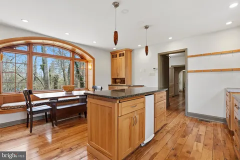a kitchen with kitchen island granite countertop wooden floors and a view of living room