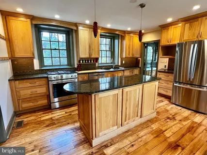 a kitchen with stainless steel appliances granite countertop a refrigerator a stove and a wooden floors