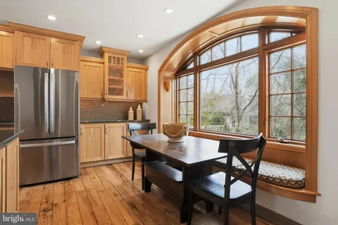 a kitchen with stainless steel appliances granite countertop a stove a refrigerator a dining table and chairs with wooden floor