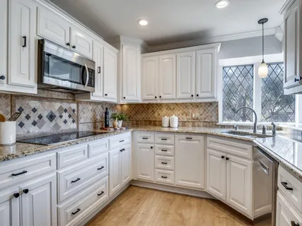 a kitchen with granite countertop white cabinets and stainless steel appliances
