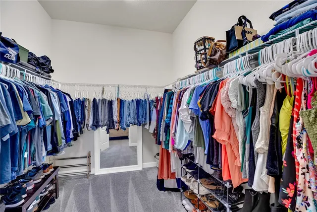 a view of walk in closet with clothes and shoes