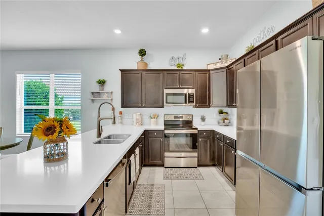 a kitchen with stainless steel appliances granite countertop a sink a stove top oven a refrigerator a stove with island and chairs