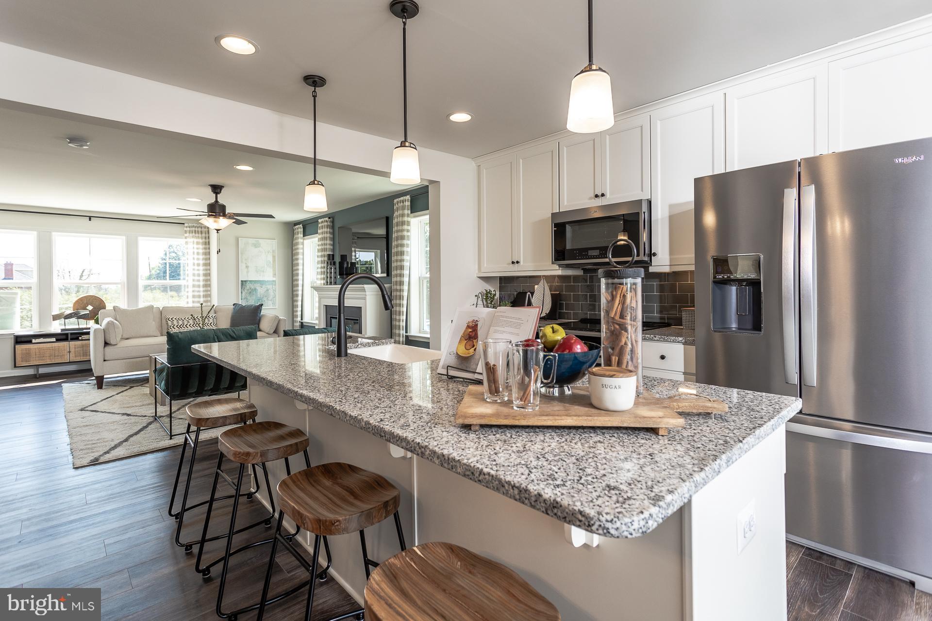 a kitchen with stainless steel appliances granite countertop a refrigerator a stove and a wooden floors