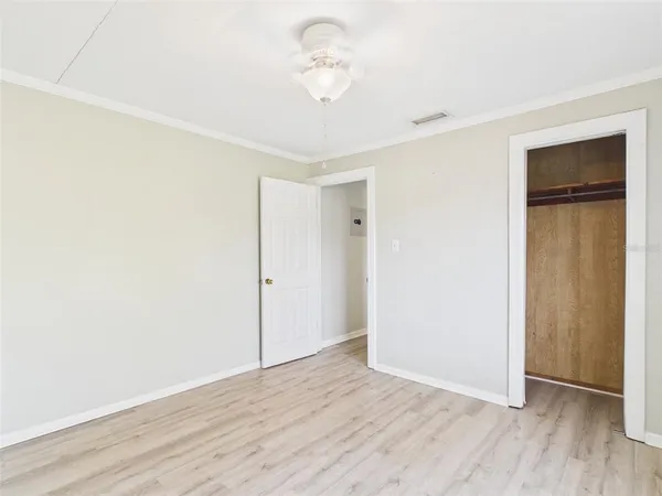 an empty room with wooden floor and fan