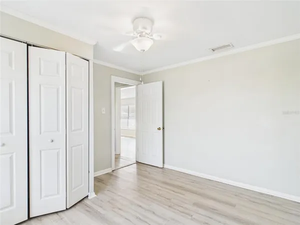 an empty room with wooden floor and fan
