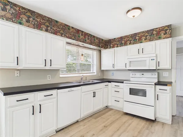 a kitchen with granite countertop white cabinets and white appliances