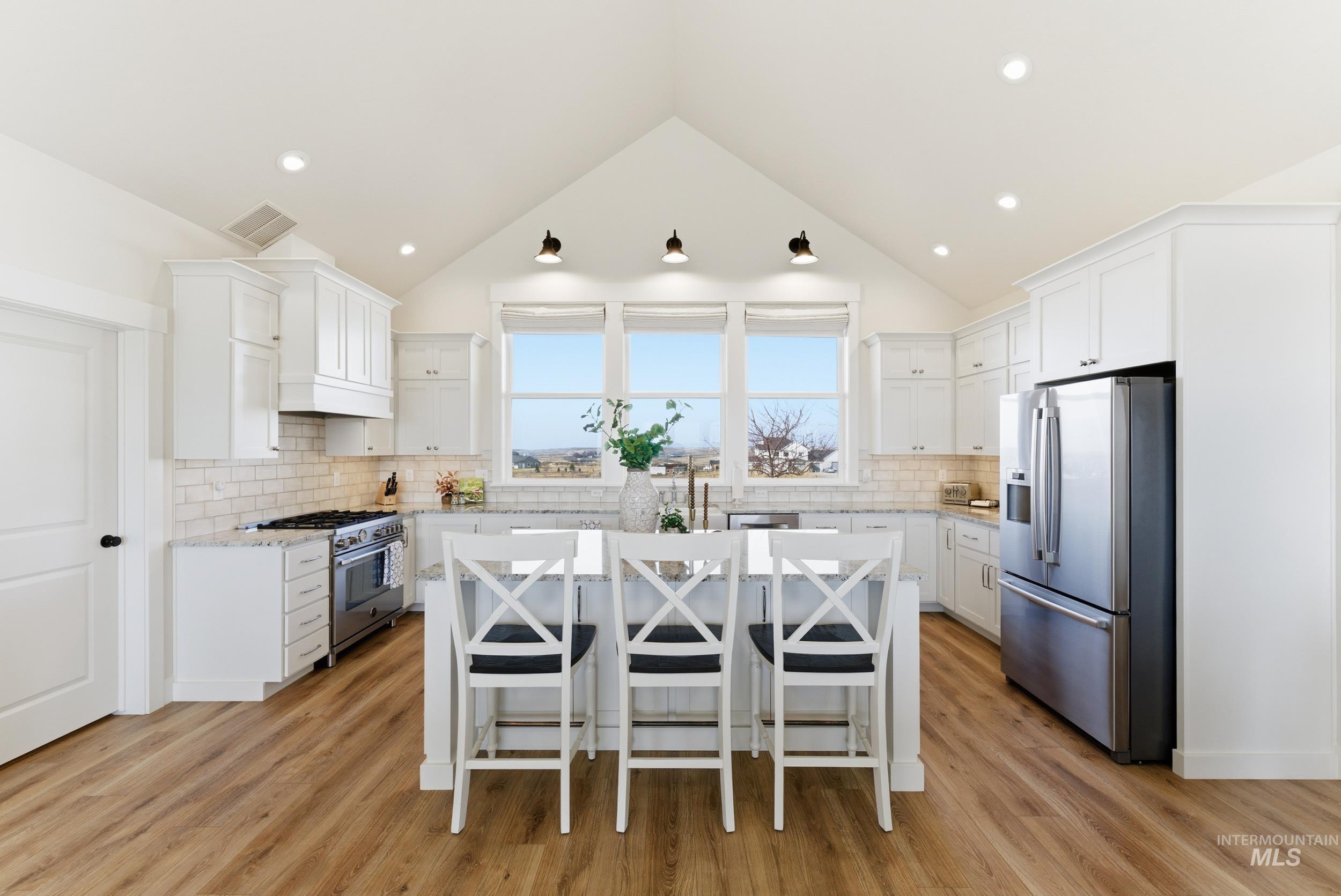 5800 Partridge Peak Avenue Caldwell, ID 83607 - Photo 12 of 50 Kitchen featuring a kitchen bar, white cabinets, stainless steel appliances, light stone countertops, and a kitchen island