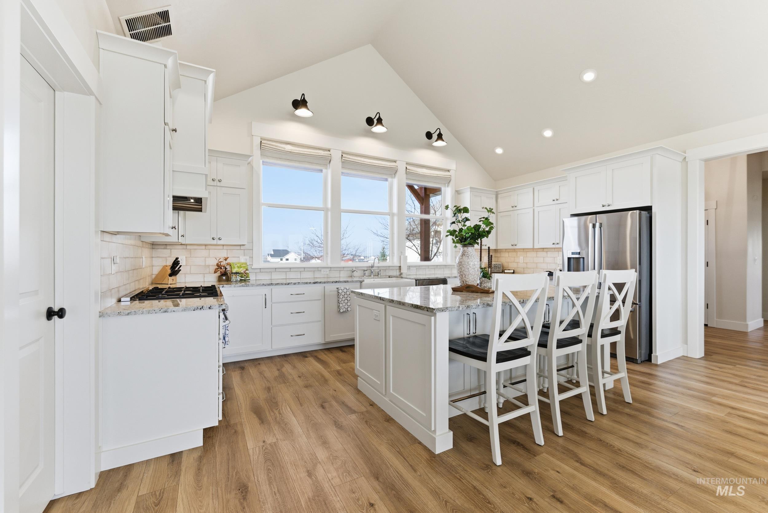 5800 Partridge Peak Avenue Caldwell, ID 83607 - Photo 13 of 50 Kitchen with a breakfast bar area, white cabinets, light stone counters, and a kitchen island