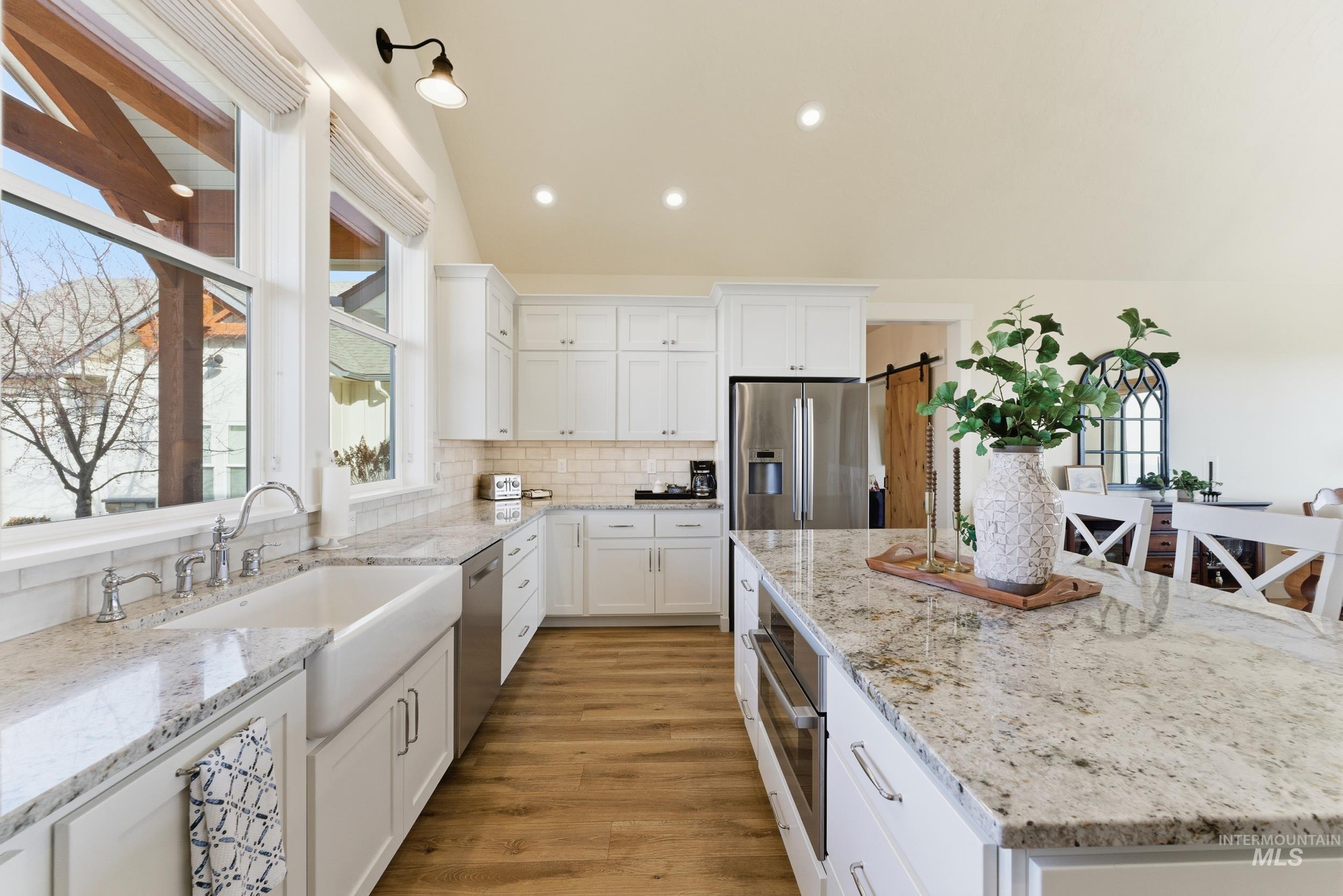 5800 Partridge Peak Avenue Caldwell, ID 83607 - Photo 16 of 50 Kitchen with white cabinetry, light stone counters, light wood-style floors, a kitchen island, and stainless steel appliances