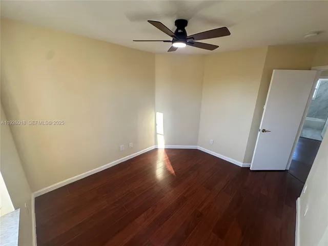an empty room with wooden floor and a ceiling fan