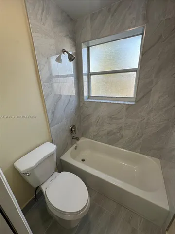 a white toilet sitting next to a bath tub