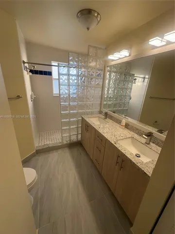 a bathroom with a granite countertop sink toilet and shower