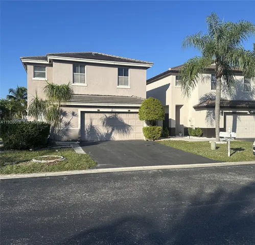 a view of a house with a yard and palm trees