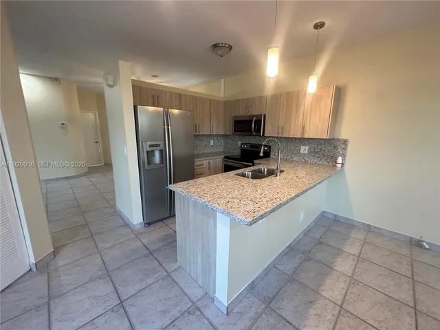 a kitchen with stainless steel appliances granite countertop a sink and a refrigerator