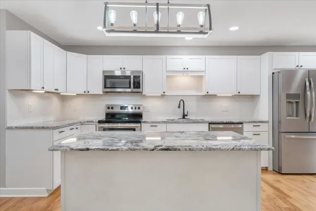a kitchen with white cabinets and stainless steel appliances