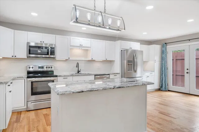 a large kitchen with granite countertop a stove top oven a sink dishwasher and a fireplace with wooden floor