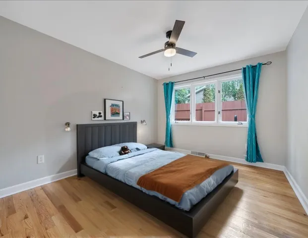 an empty room with wooden floor fireplace and windows