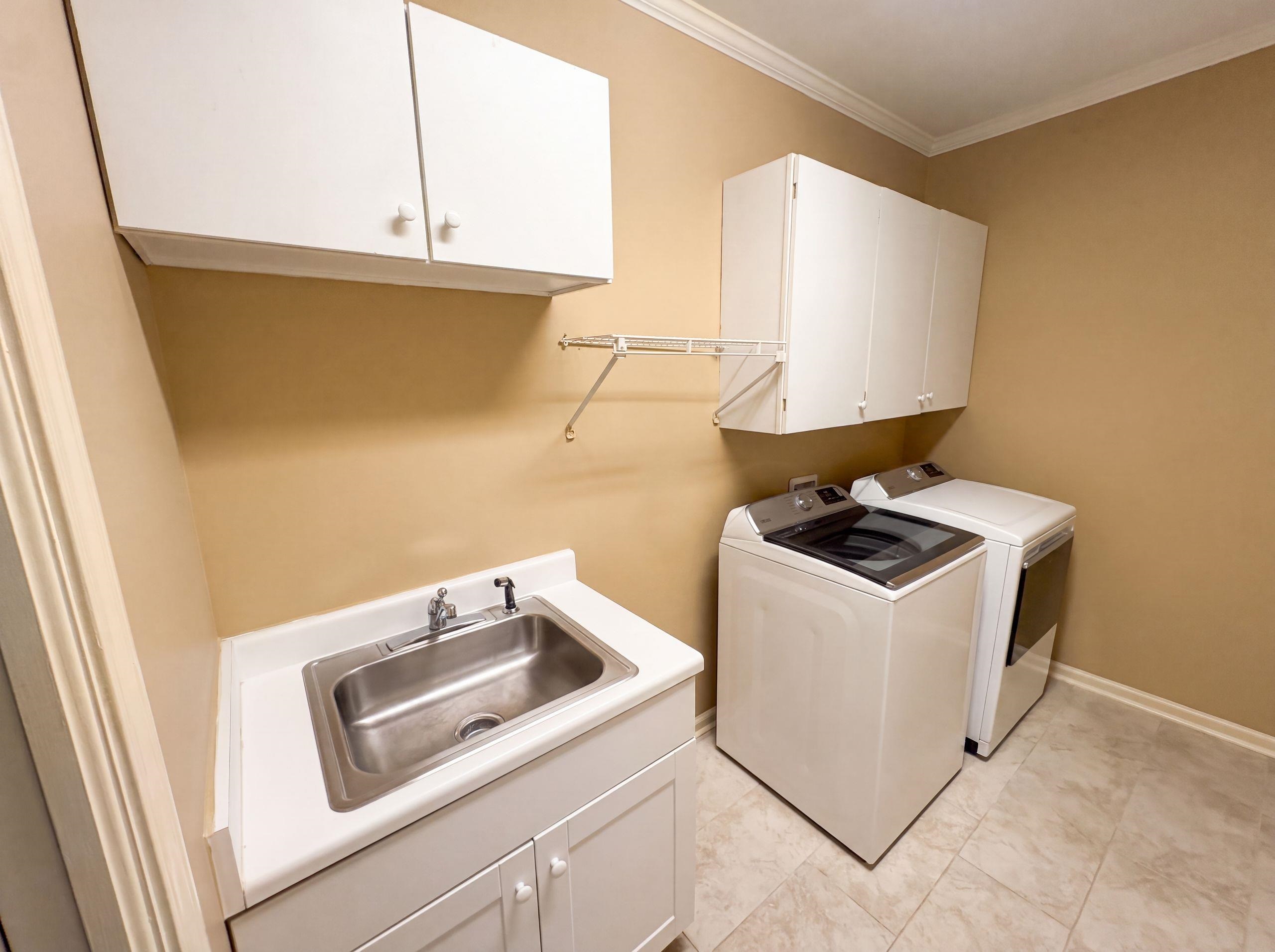 9424 Gotten Road Germantown, TN 38139 - Photo 25 of 27 Laundry area featuring white cabinetry, a utility sink with a stainless steel basin, a white countertop, and tile flooring