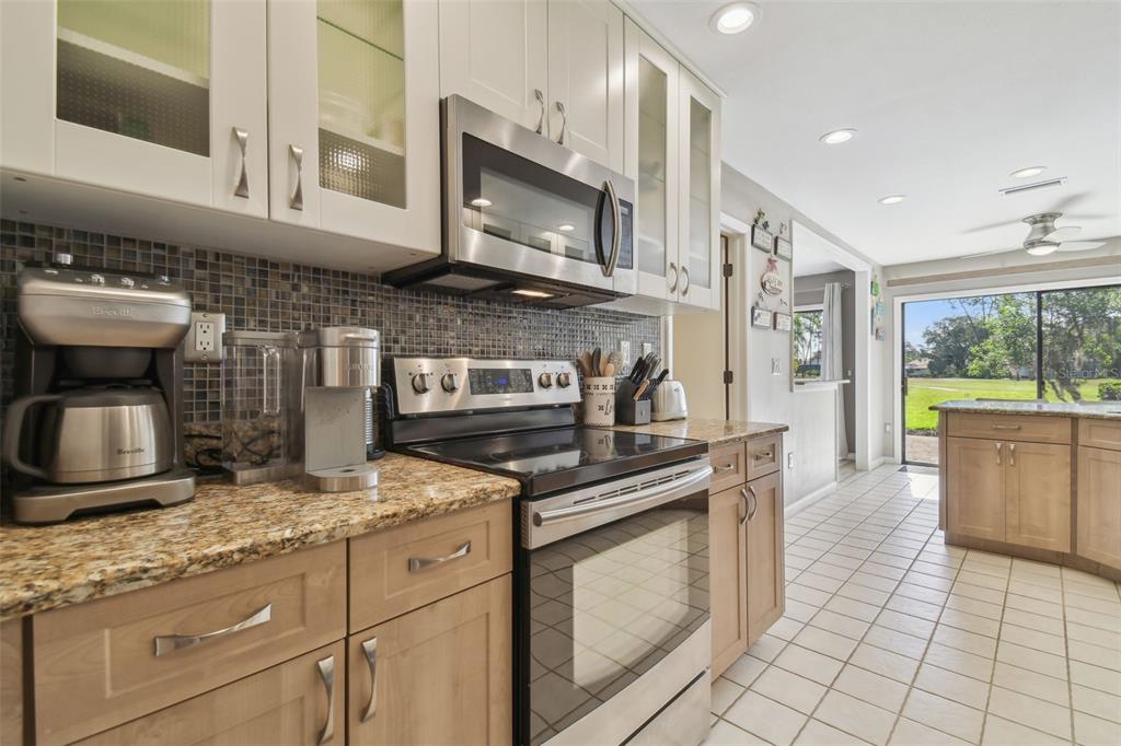 5434 Kemkerry Road Wesley Chapel, FL 33543 - Photo 3 of 56 a kitchen with stainless steel appliances granite countertop a stove a sink and a microwave