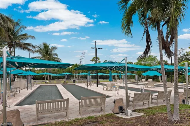 a patio with tables and chairs pool and a fire pit with wooden fence
