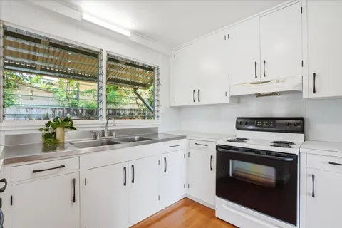 a kitchen with granite countertop white cabinets appliances and a large window