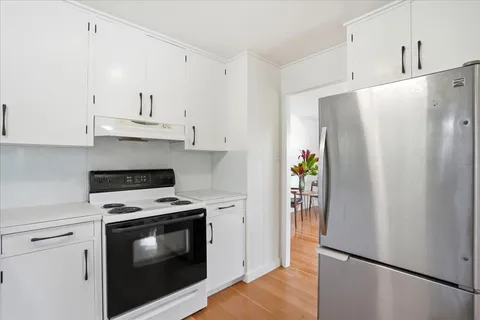 a kitchen with stainless steel appliances a refrigerator a stove and white cabinets