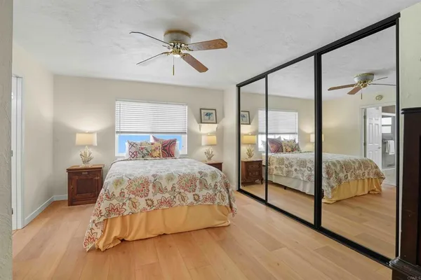 a bedroom with a bed and large mirror with wooden floor