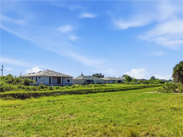 a view of a big house with a big yard and large trees