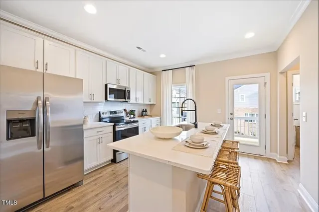 a kitchen with a refrigerator a stove cabinets and wooden floor