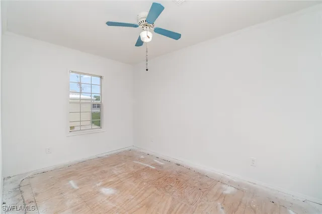 an empty room with a window and a fan