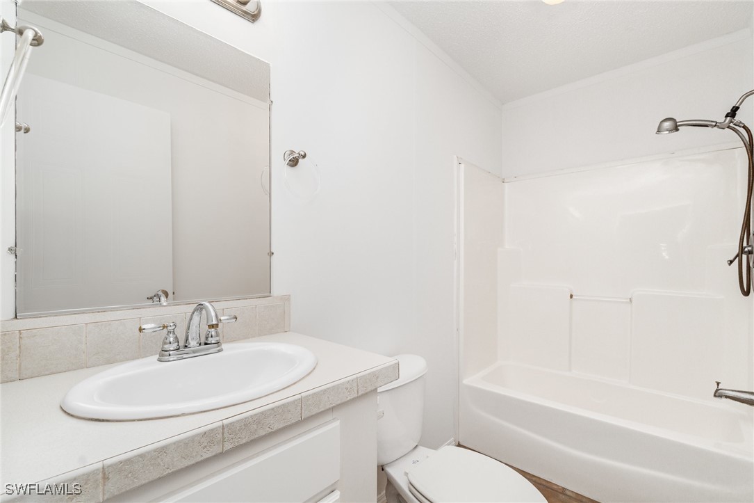 7679 Farrell Road Bokeelia, FL 33922 - Photo 22 of 34 a bathroom with a granite countertop sink toilet and a bathtub