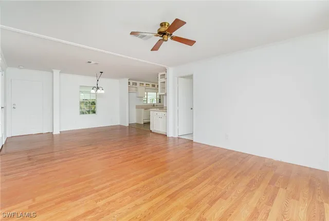 a view of empty room with wooden floor and ceiling fan