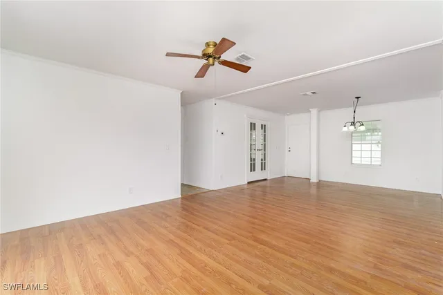 a view of empty room with wooden floor and ceiling fan