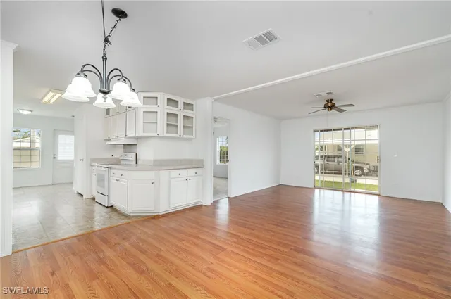 a large kitchen with cabinets wooden floor and a chandelier