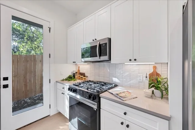 a kitchen with stainless steel appliances white cabinets and a stove top oven