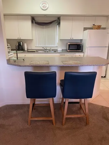 a kitchen with stainless steel appliances kitchen island granite countertop a sink dishwasher a stove a refrigerator a microwave oven with white cabinets and wooden floor