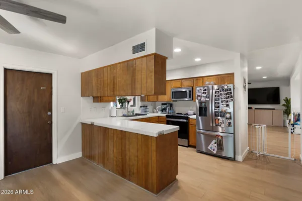 a kitchen with stainless steel appliances granite countertop a refrigerator a sink dishwasher and a oven with wooden floor