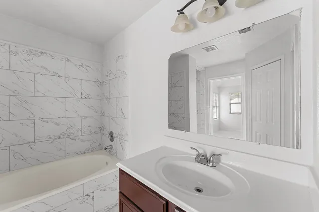 a bathroom with a bathtub shower sink and mirror