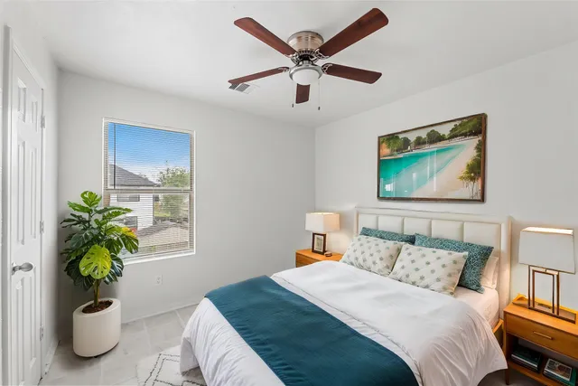 a bed room with a bed a painting and a potted plant