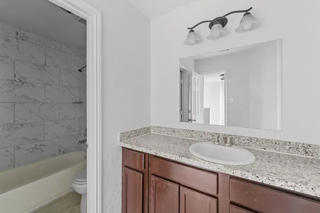 a bathroom with a granite countertop sink and a mirror