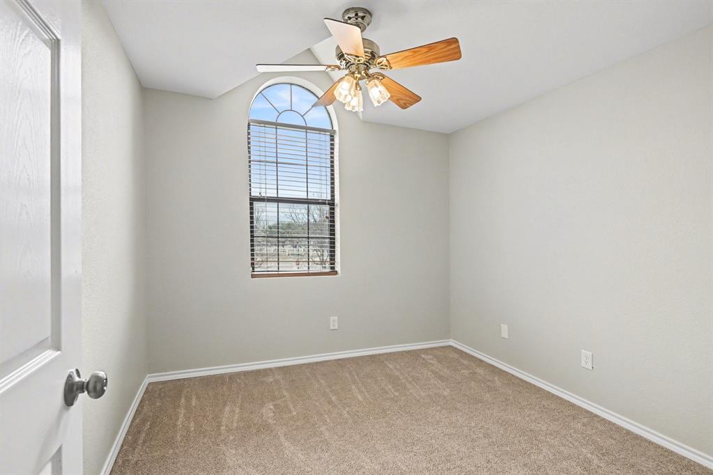 10101 Round Hill Road Fort Worth, TX 76131 - Photo 23 of 30 an empty room with a chandelier fan and windows