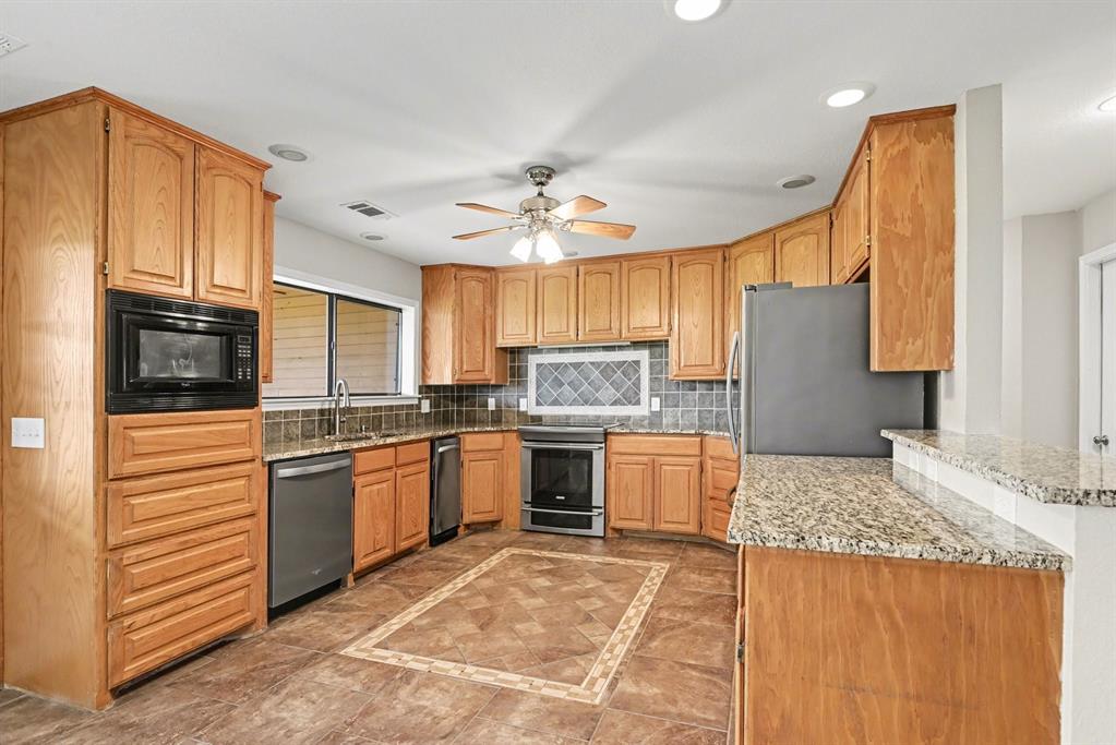 10101 Round Hill Road Fort Worth, TX 76131 - Photo 6 of 30 a kitchen with stainless steel appliances granite countertop a stove top oven a sink dishwasher and a refrigerator