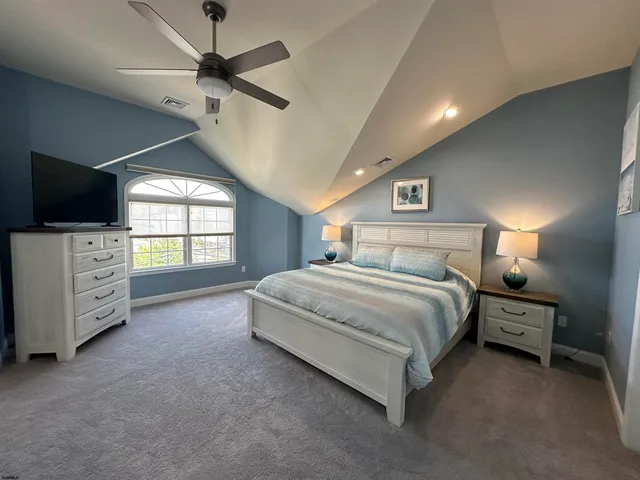 a spacious bedroom with a bed and a television on the dresser