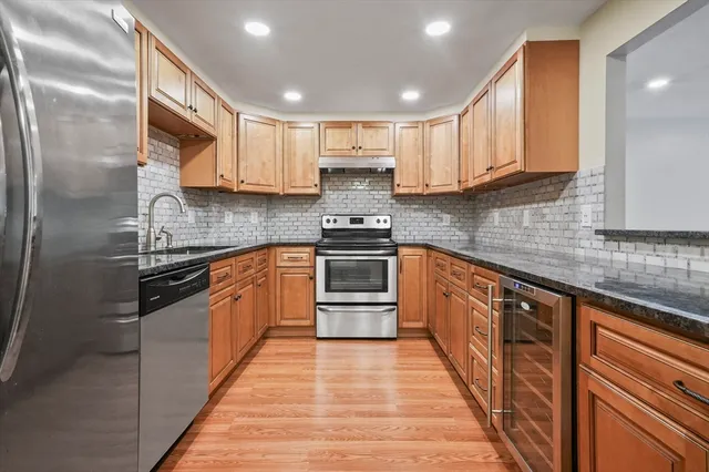a kitchen with stainless steel appliances granite countertop a stove a sink and a refrigerator