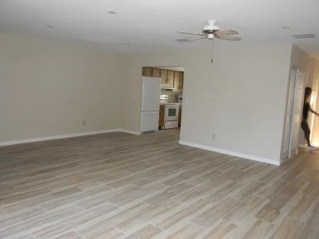 an empty room with wooden floor chandelier fan and windows
