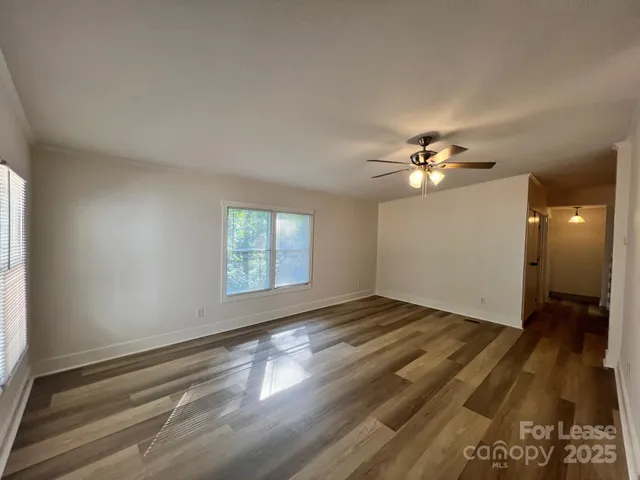 a view of an empty room with wooden floor and a window