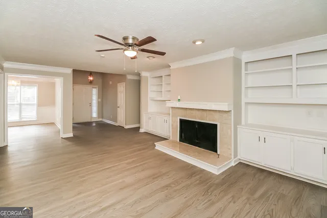 a view of a livingroom with a fireplace a ceiling fan and windows